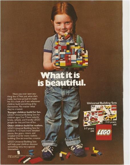 Une petite fille en jeans et baskets, debout, face au spectateur présente la construction qu&#039;elle a réalisée avec des briques Lego.